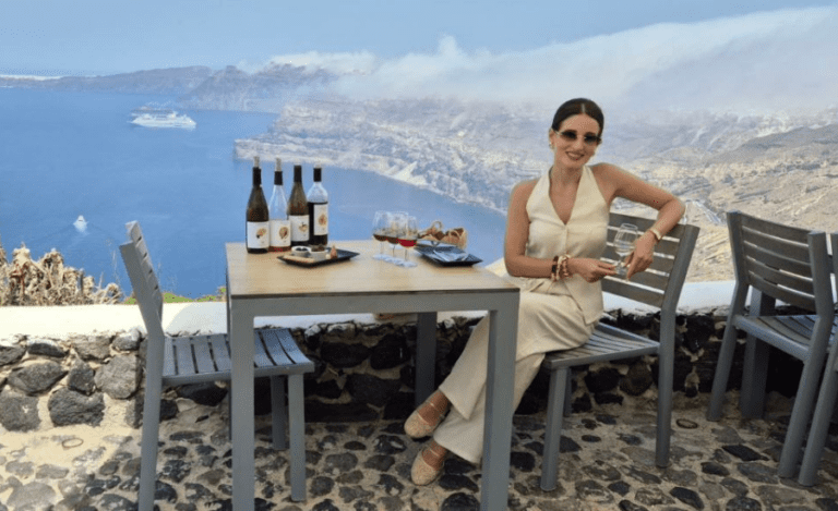 woman enjoying lunch with wine pairing overlooking the Santorini Caldera during a Terroir Santorini Wine Tour
